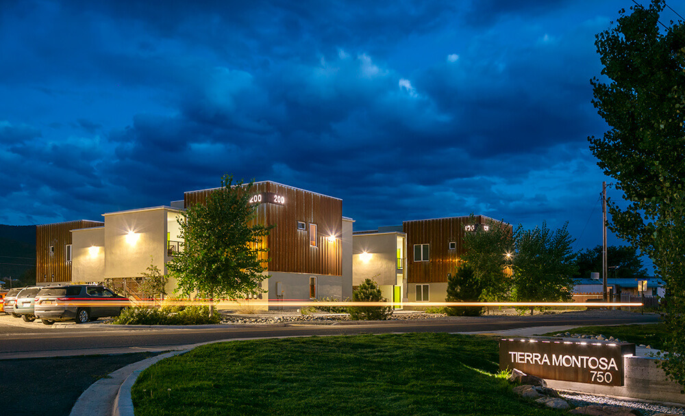 The lit Tierra Montosa sign at 750 Gusdorf Road with homes glowing under a dramatic night sky